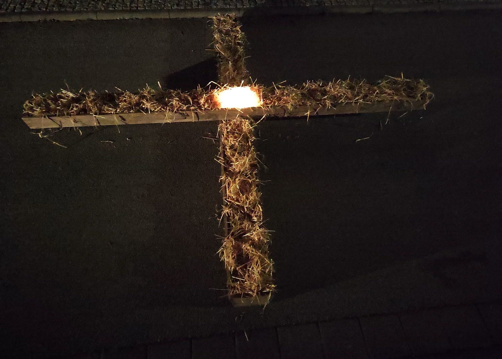 Foto Kreuz aus zwei Futtertrögen mit Stroh und Lichtquelle